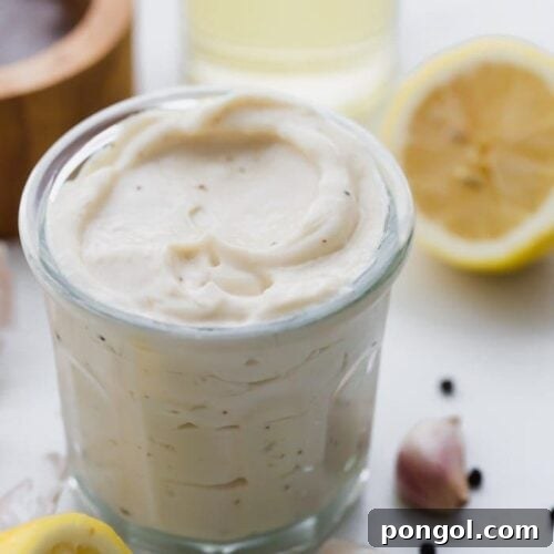 Whole30 Caesar dressing in a jar with lemons, garlic, peppercorns, and light tasting olive oil in a bottle