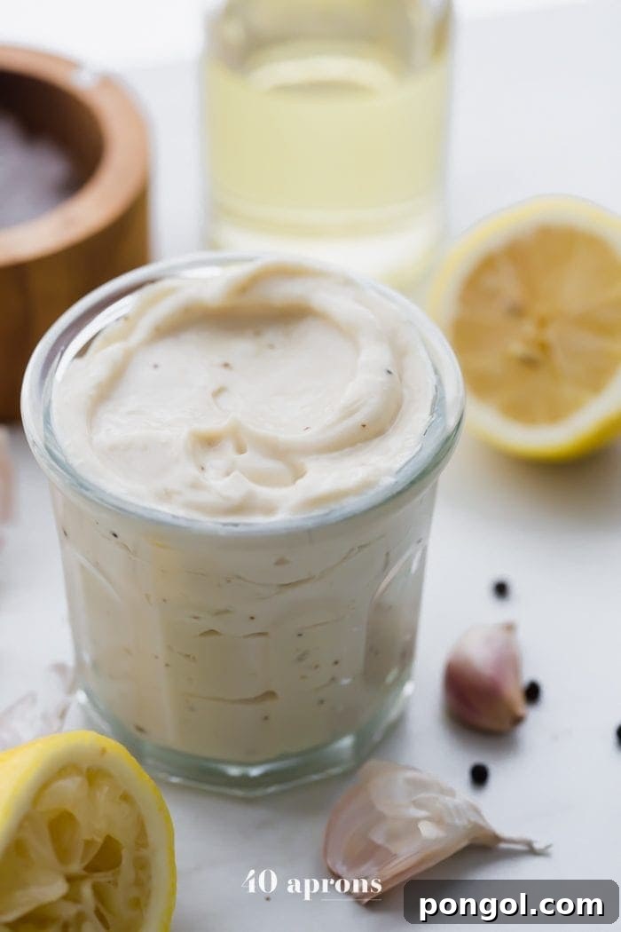 Whole30 Caesar dressing in a jar with lemons, garlic, peppercorns, and light tasting olive oil in a bottle
