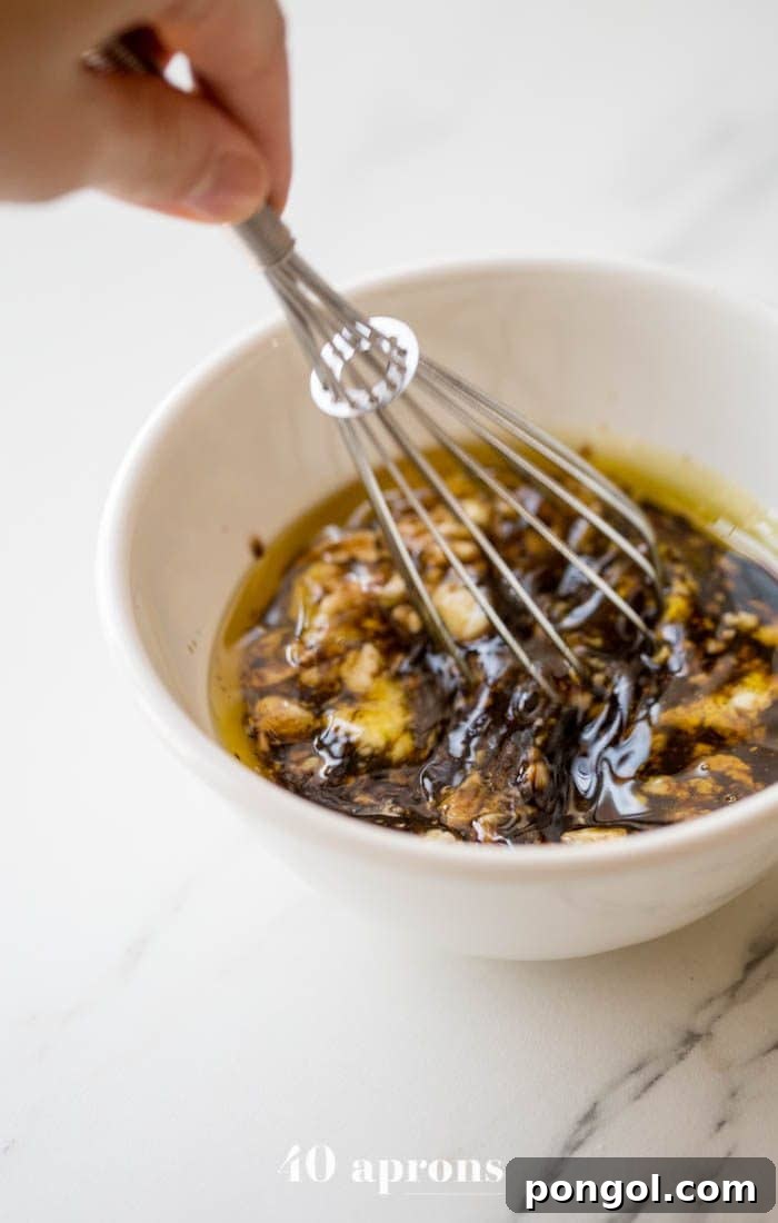 Hands whisking creamy Whole30 balsamic dressing in a bowl, showcasing its smooth texture