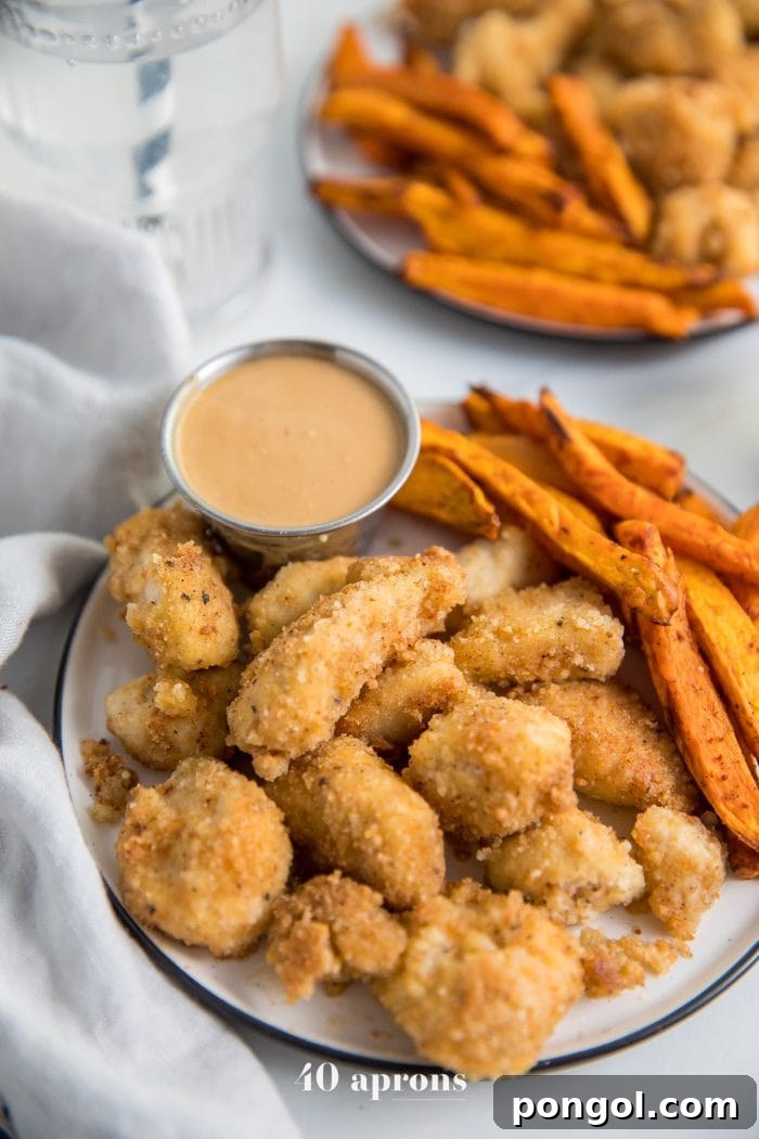Paleo Whole30 chicken nuggets recipe on a plate with dipping sauce and sweet potato fries