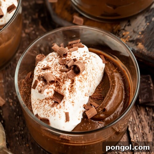 Overhead angled view of 4 jars of avocado chocolate mousse topped with whipped coconut cream.