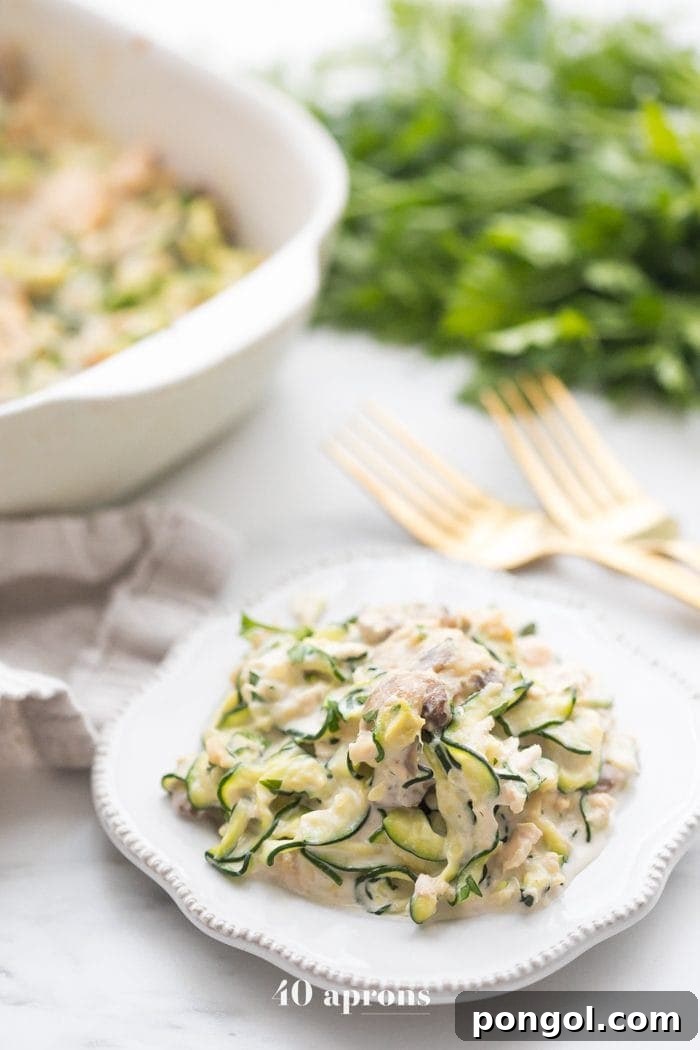 Whole30 Zoodle Tuna Bake 2 Whole30 tuna zoodle casserole on a plate next to a casserole dish, showcasing its rich and creamy texture with golden-brown mushrooms.