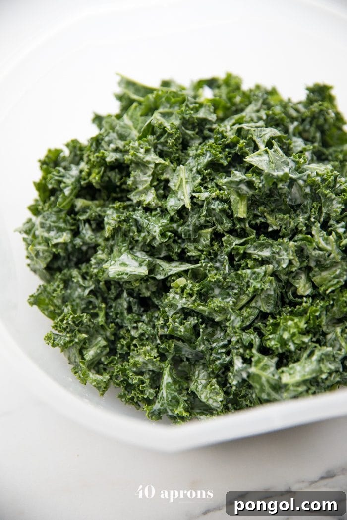 A fresh and vibrant Kale Caesar Salad in a large bowl, drizzled with dressing, ready to be enjoyed at a Whole30 picnic.