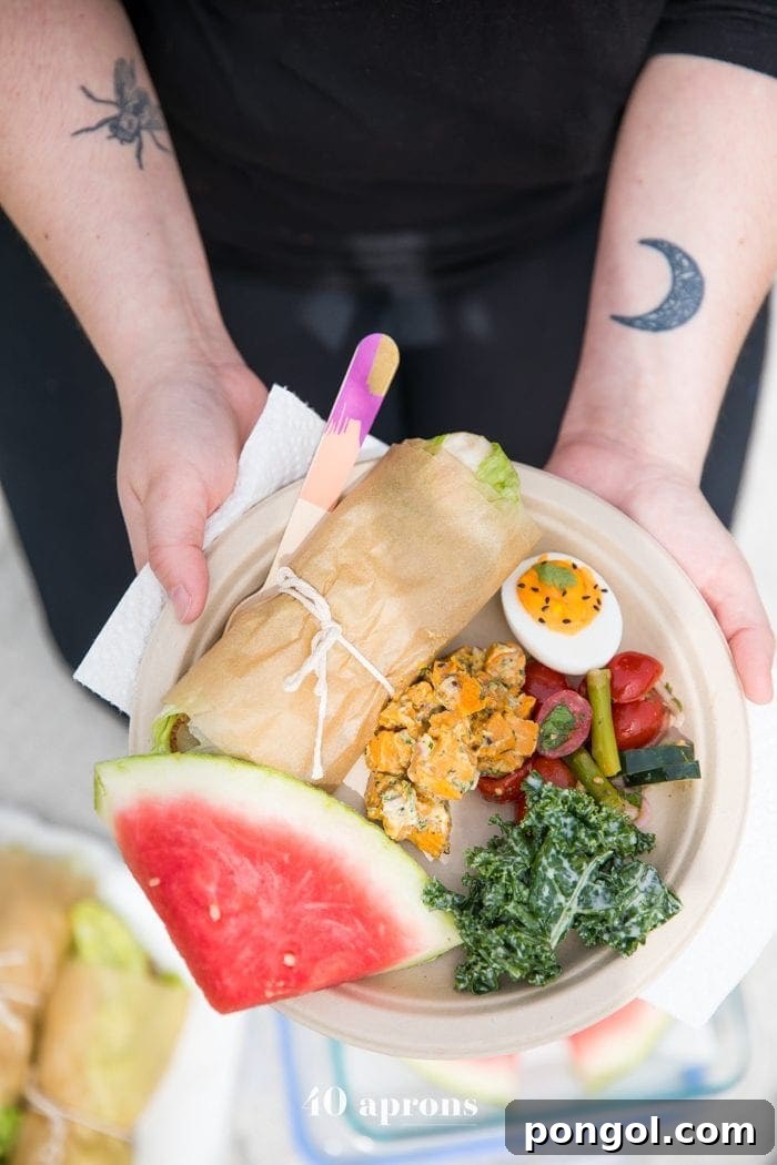 A close-up shot of a plate brimming with delicious Whole30 picnic food, including lettuce wraps, sweet potato salad, and fresh berries.