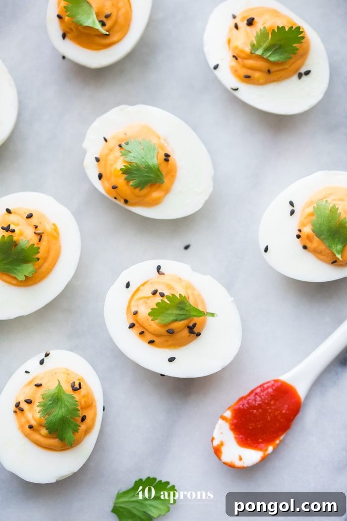 A close-up view of a Sriracha Deviled Egg, perfectly piped and garnished, ready to be served as a Whole30 and Paleo treat.