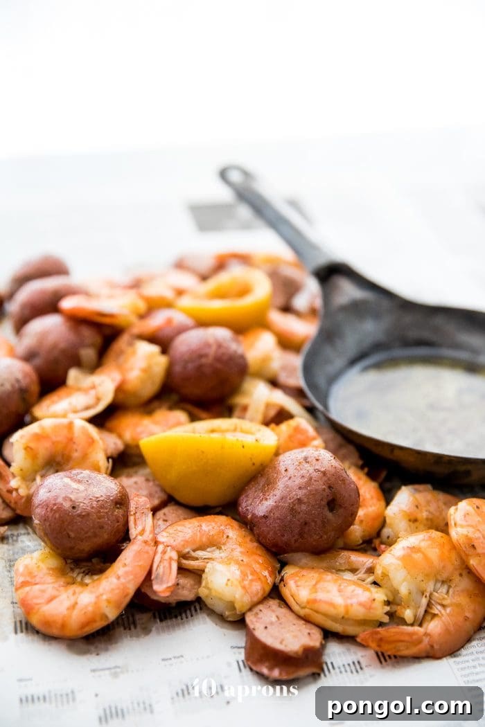 Overhead view of a vibrant Whole30 shrimp boil, featuring perfectly cooked shrimp, sliced kielbasa, red potatoes, and lemon wedges, ready to be enjoyed on newspaper