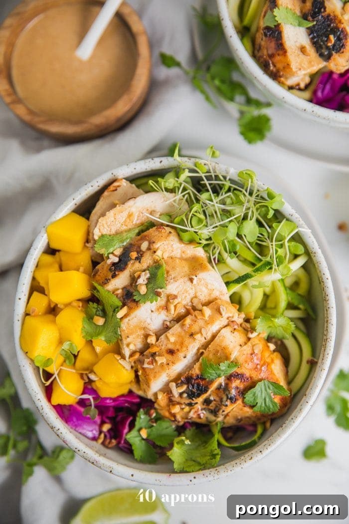 Whole30 Thai chicken zoodle bowls with "peanut sauce" in a bowl with garnishes