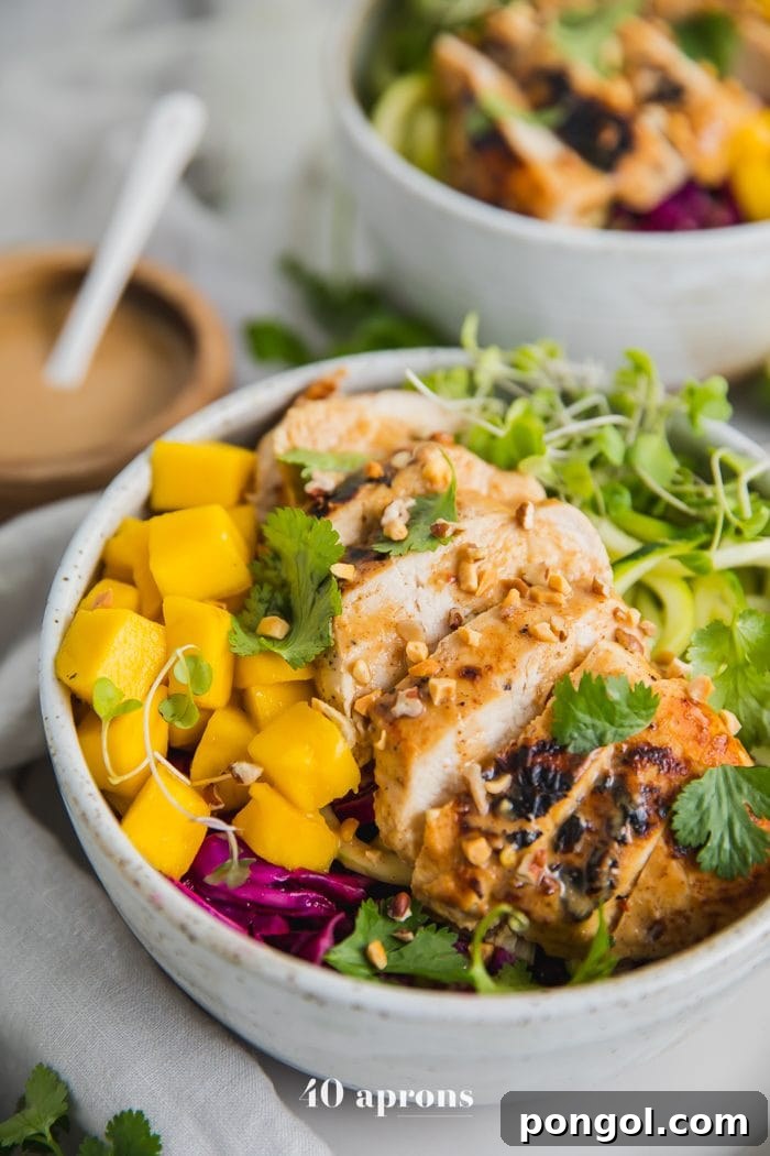 Whole30 Thai chicken zoodle bowls with "peanut sauce" in a bowl with garnishes