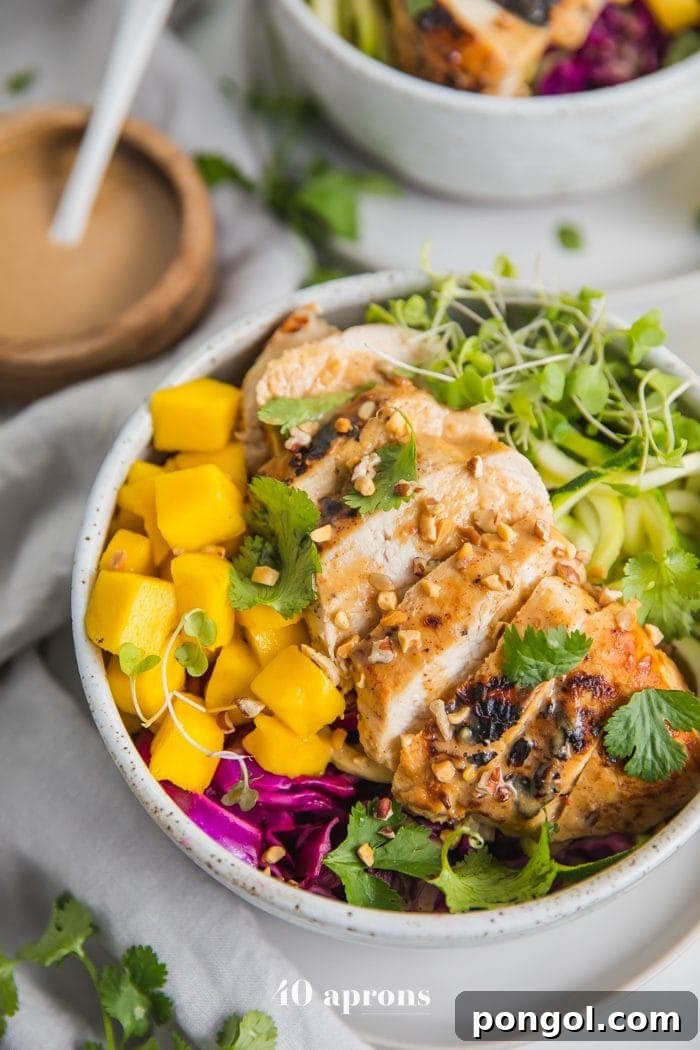 Whole30 Thai chicken zoodle bowls with "peanut sauce" in a bowl with garnishes