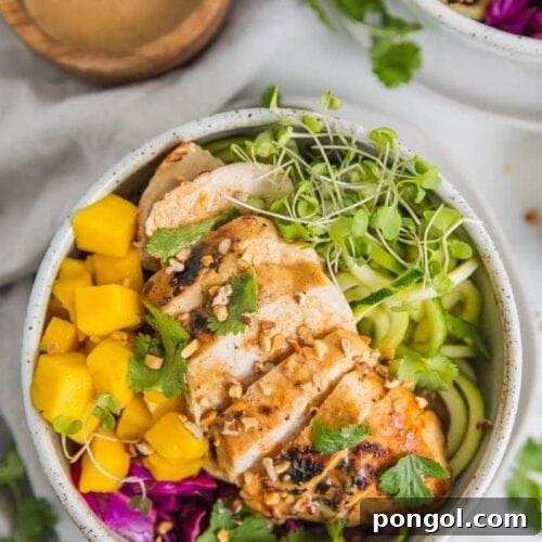 Whole30 Thai chicken zoodle bowls with "peanut sauce" in a bowl with garnishes