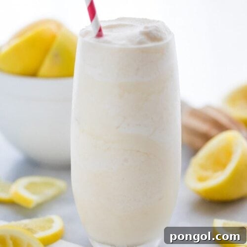 Healthy frosted lemonade in a glass with a straw and lemons in the background