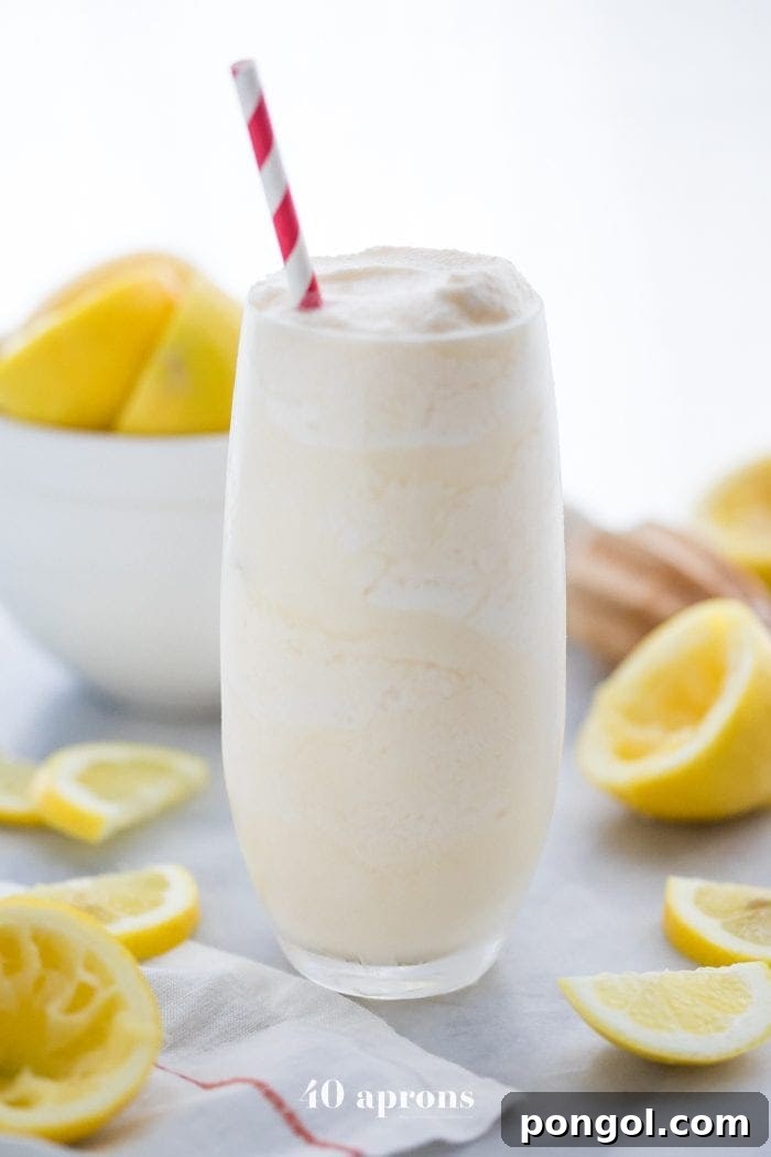 Healthy Chick Fil A frosted lemonade in a glass with a straw and lemons in the background