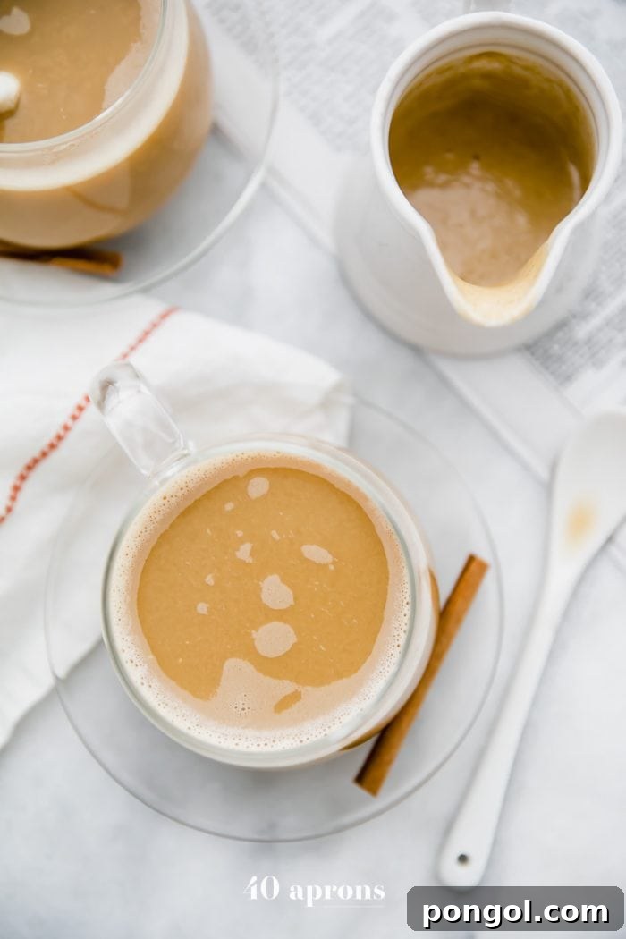 Whole30 pumpkin spice creamer stirred into a cup of coffee with a cinnamon stick and second cup of coffee in the background