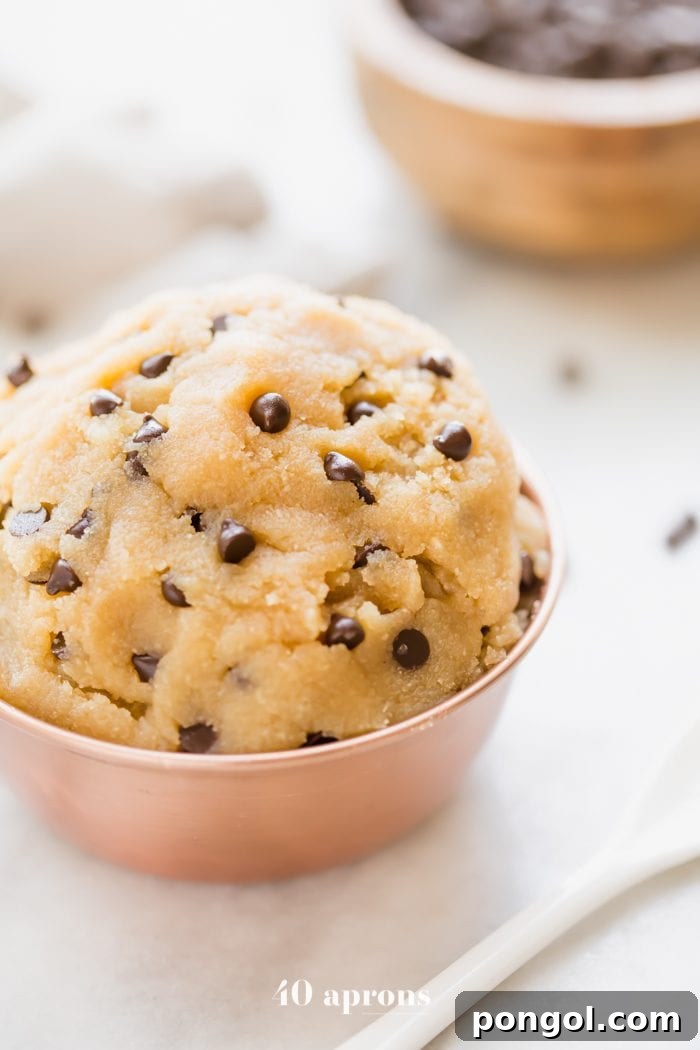 Vegan healthy cookie dough in a copper bowl with a bowl of chocolate chips in the corner