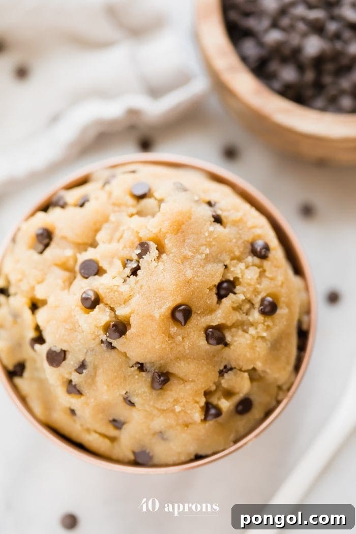 Vegan healthy cookie dough in a copper bowl with a bowl of chocolate chips in the corner