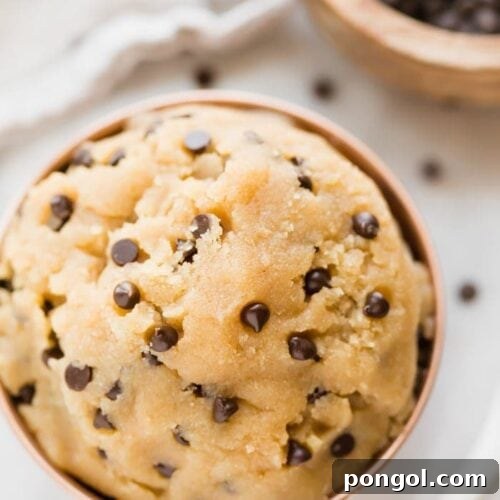 Healthy cookie dough in a copper bowl with a bowl of chocolate chips in the corner