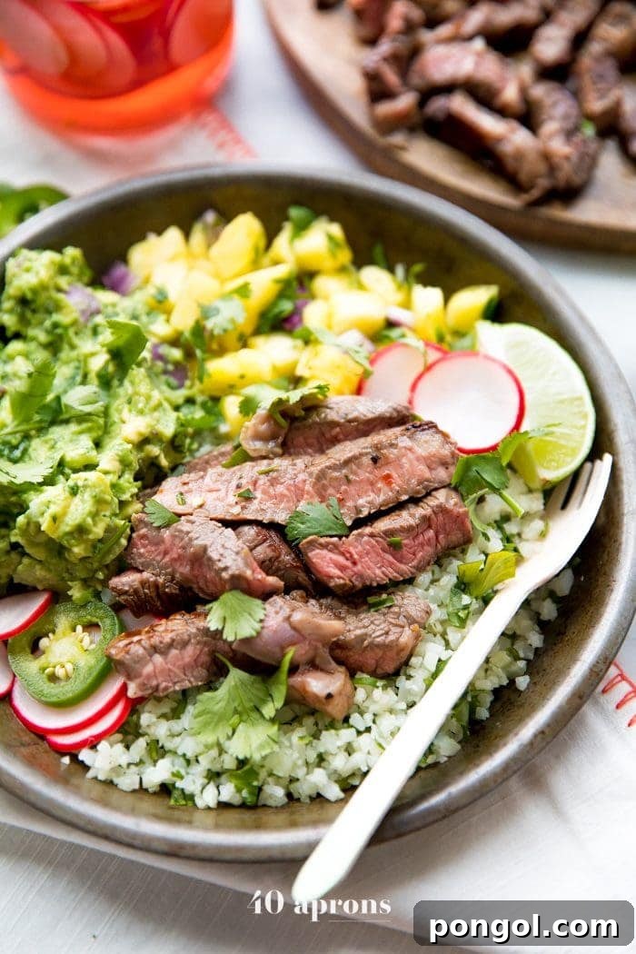 Whole30 Steak Taco Bowls: Tender steak, creamy guacamole, sweet pineapple salsa, quick pickled radishes, and cilantro-lime cauliflower rice for a healthy, low-carb Mexican dinner.