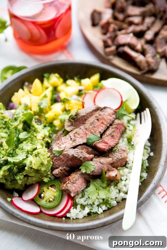 A vibrant Whole30 Steak Taco Bowl with juicy steak, creamy guacamole, sweet pineapple salsa, and crunchy pickled radishes on a bed of cilantro-lime cauliflower rice.