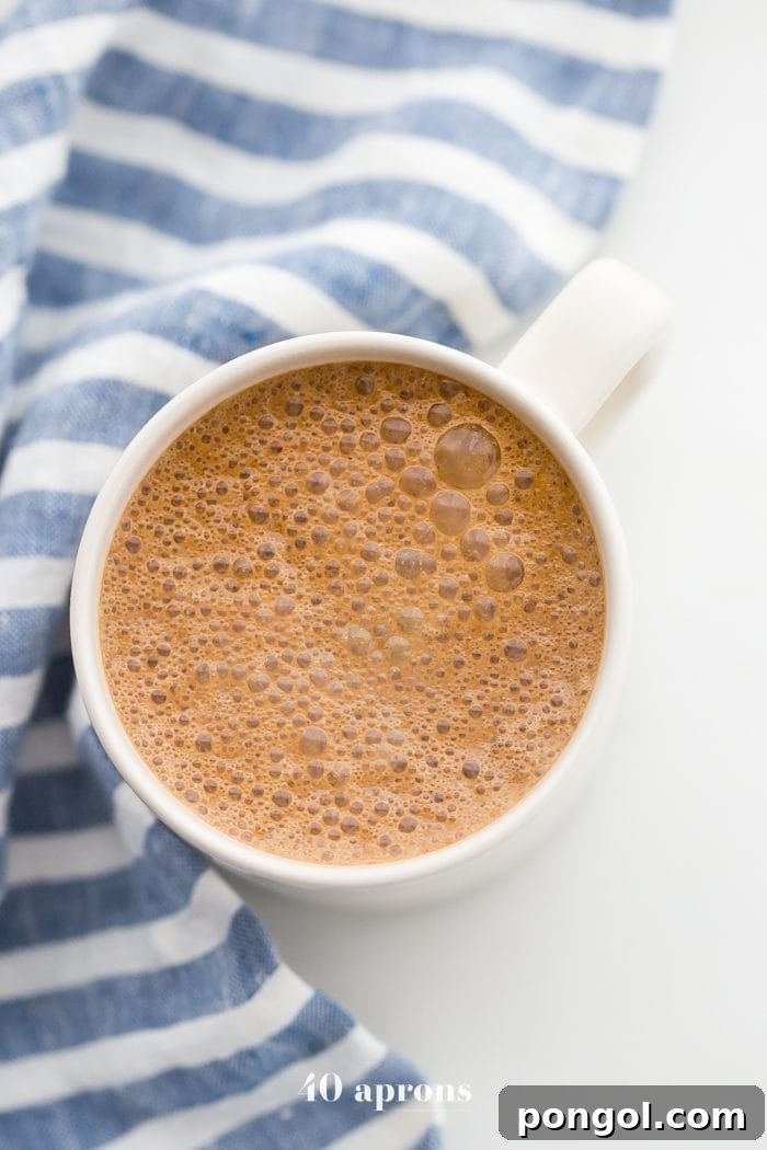 A cozy close-up of a miracle maca latte mug, with a blue-striped towel peeking from behind, emphasizing its comforting presence