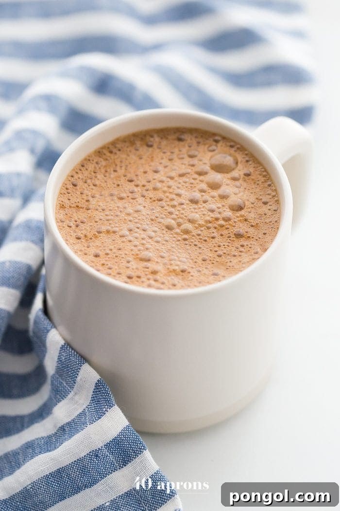 A trio of miracle maca latte mugs, each nestled against a blue-striped towel, showcasing the drink's inviting warmth and comforting appeal