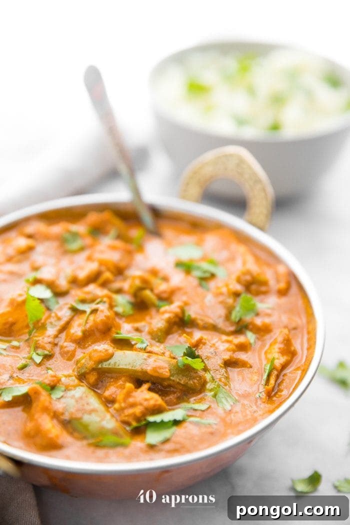 Instant Pot chicken tikka masala in a copper serving bowl with chopped cilantro and cauliflower rice in the background