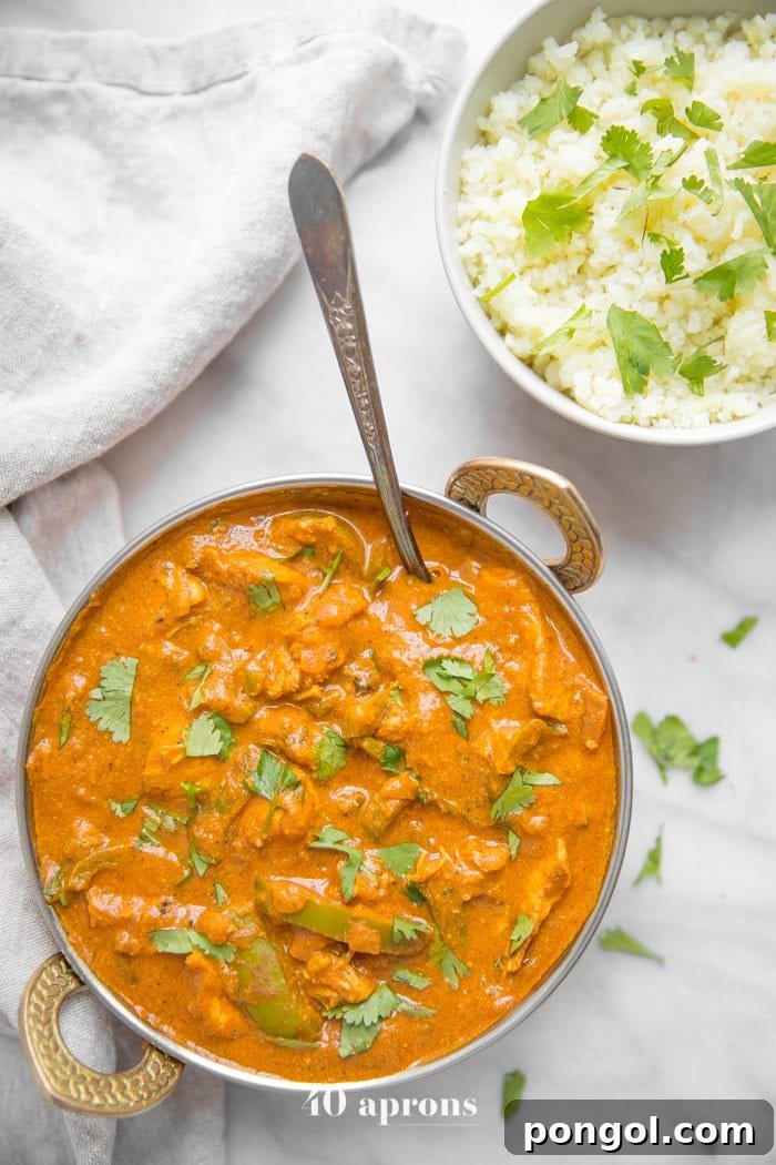Instant Pot chicken tikka masala in a copper serving bowl with chopped cilantro and cauliflower rice