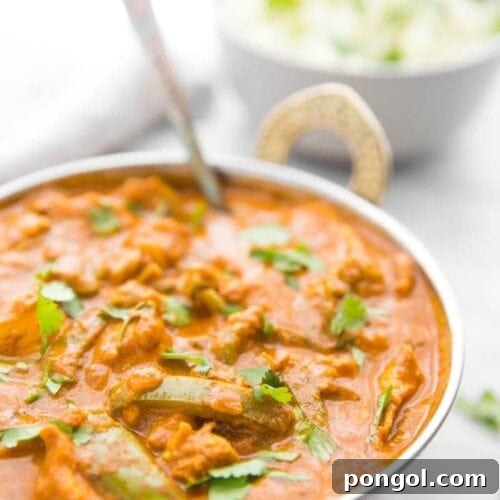 Instant Pot chicken tikka masala in a copper serving bowl with chopped cilantro and cauliflower rice in the background