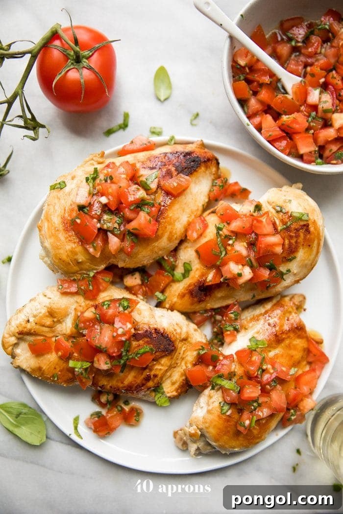Bruschetta chicken on a plate with fresh basil, bruschetta, and more bruschetta chicken in background