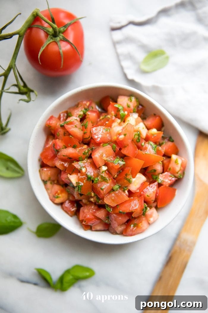 Bowl of fresh bruschetta with tomatoes, basil, and garlic, Tomatoes and fresh basil off to the side