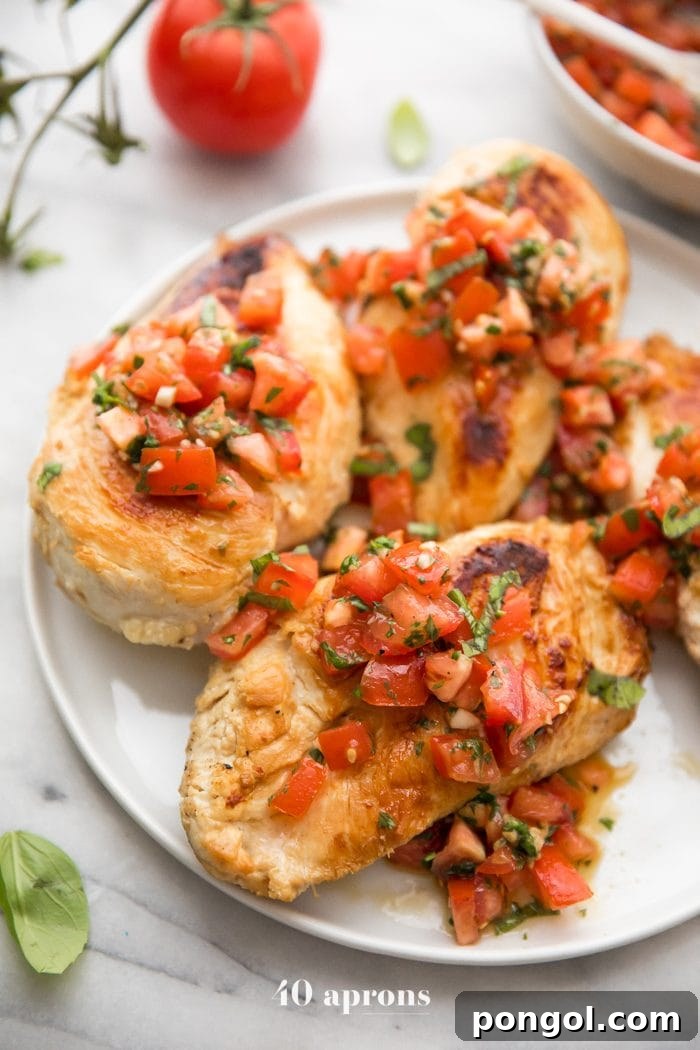 Bruschetta chicken on a plate with fresh basil, bruschetta, and more bruschetta chicken in background