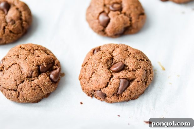 3 stacked Paleo freshly baked Double Chocolate Fudge Cookies on a parchment paper-lined tray.