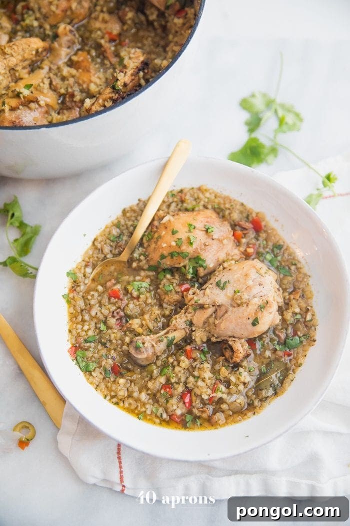 Healthy Spanish chicken and cauliflower rice stew in a rustic bowl, with a large cooking pot in the background filled with more stew, showcasing rich textures and colors.