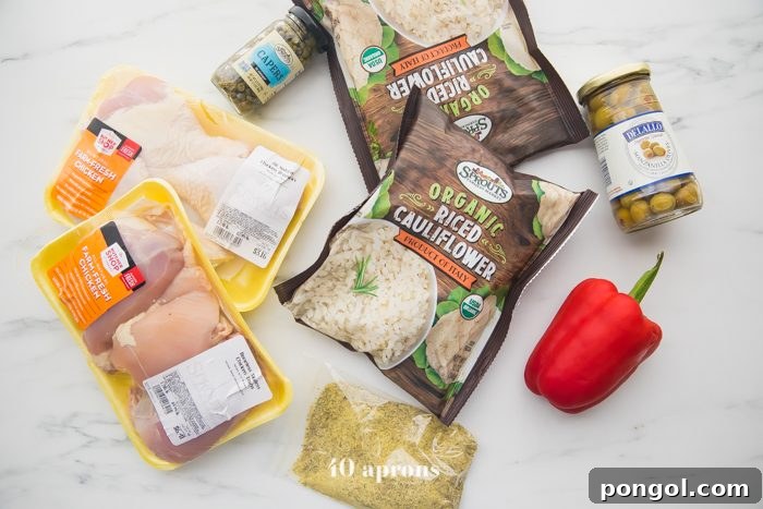 Individual ingredients for healthy Spanish chicken and cauliflower rice stew laid out on a surface, including chicken pieces, various spices, fresh vegetables, olives, and a bag of cauliflower rice.