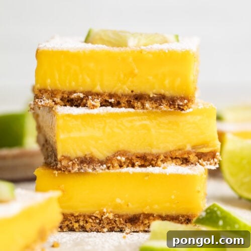 Three square paleo lime bars stacked on top of each other, garnished with powdered sugar and a lime wedge.
