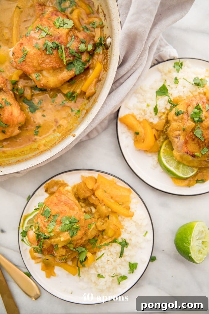 Coconut curry turmeric chicken on a plate with cilantro garnish and a lime to the side