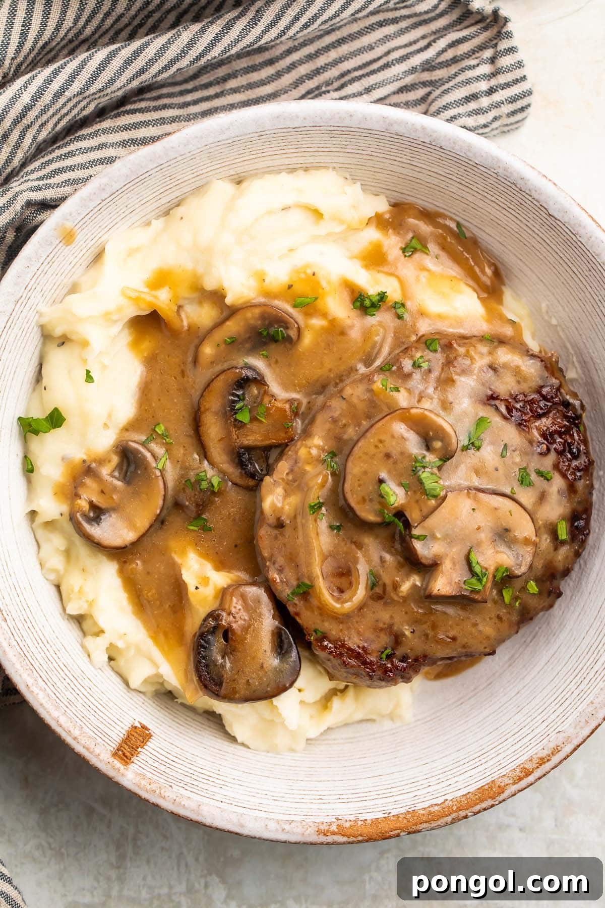 A large bowl of Whole30 salisbury steak and mashed potatoes smothered in plenty of brown gravy.