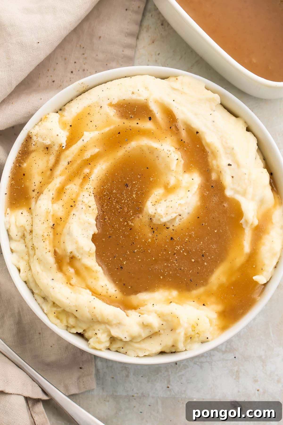 Top-down view of a large bowl of mashed potatoes topped with rich brown paleo gravy.