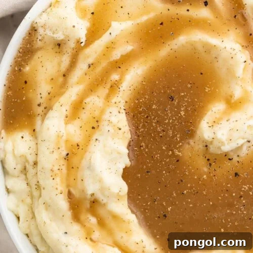 Top-down view of a large bowl of mashed potatoes topped with rich brown paleo gravy.