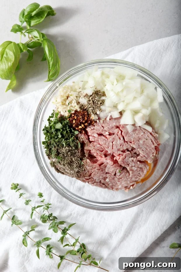 ingredients for Whole30 Meatballs in a glass bowl ready to be mixed.