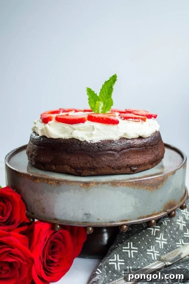 Flourless Keto Chocolate Torte Dessert topped with whipped cream on a cake stand