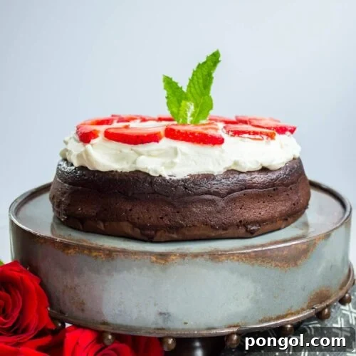 Keto Flourless Chocolate Dessert Torte topped with whipped cream on a cake stand