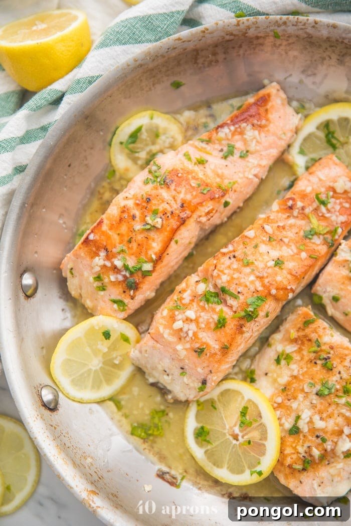 Lemon garlic salmon in a skillet, showcasing the delicious sauce and lemon slices.