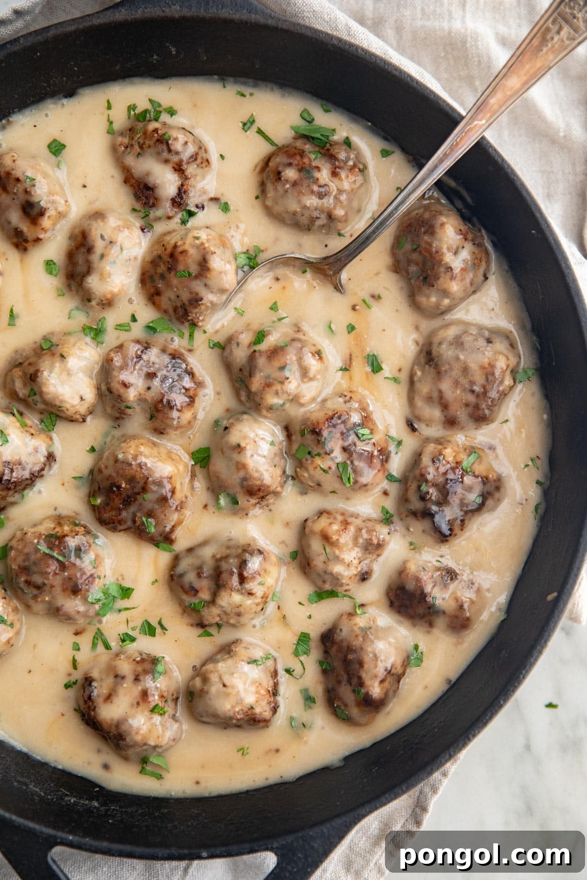 Whole30 Swedish meatballs in a large cast-iron skillet with plenty of creamy sauce.