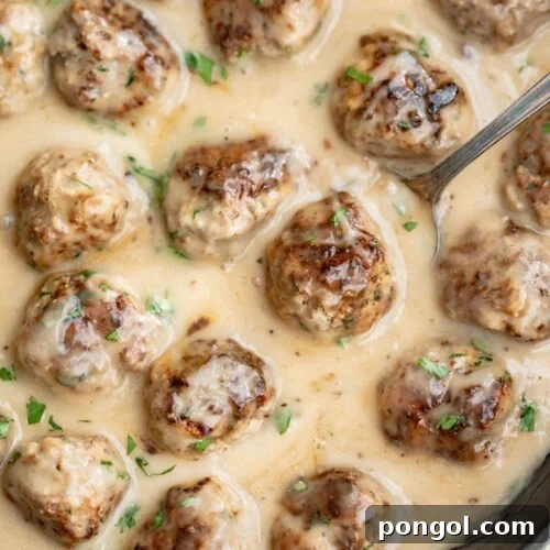 Whole30 Swedish meatballs in a large cast-iron skillet with plenty of creamy sauce.
