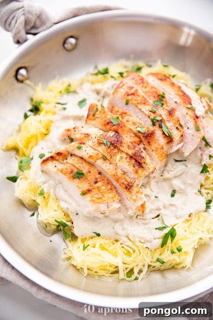 Healthy Whole30 chicken alfredo with spaghetti squash in a skillet topped with parsley