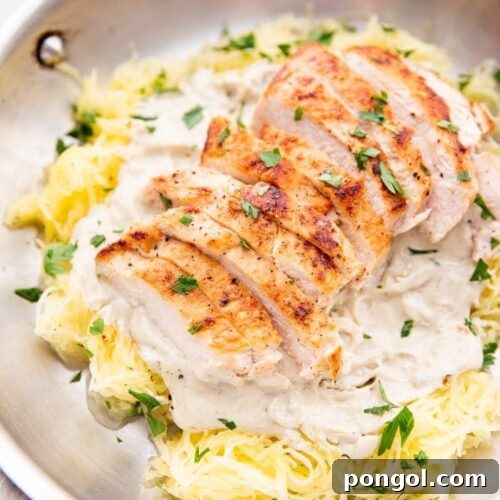 Healthy Whole30 chicken alfredo with spaghetti squash in a skillet topped with parsley