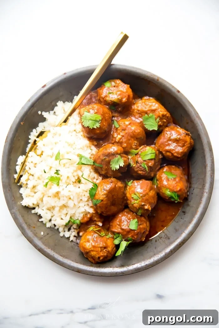 Indian meatballs with creamy sauce next to cauliflower rice topped with cilantro in a grey dish