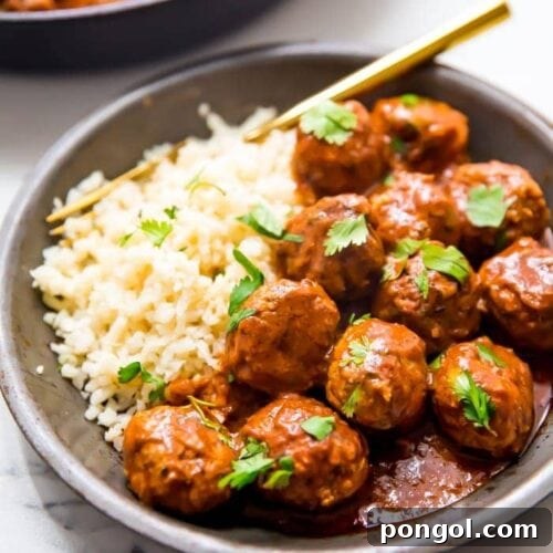 Indian meatballs with creamy sauce next to cauliflower rice topped with cilantro in a grey dish
