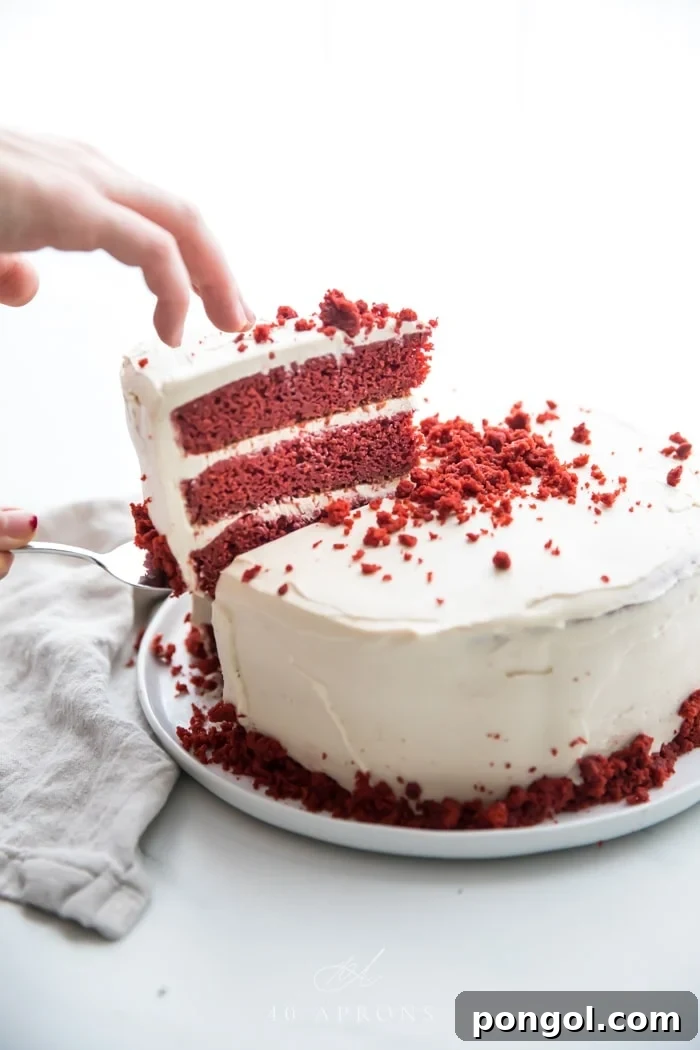 Slice of three layer gluten free red velvet being lifted out of whole cake