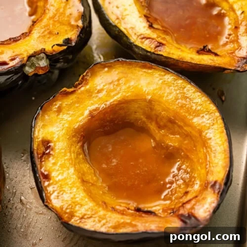 Roasted acorn squash halves with caramelized maple butter pooled in centers on baking sheet